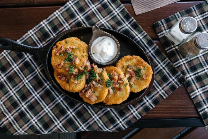 Драники со сметаной и обжаренной свиной грудинкой с луком