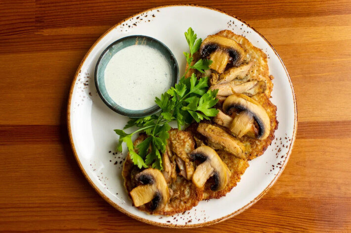 Драники с печеным куриным бедром, жареными грибами и зеленым сметанным соусом